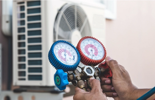 Technician using HVAC gauges to diagnose and service commercial air conditioning equipment