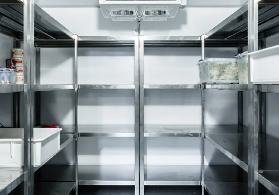 Interior of a commercial walk-in cooler with stainless steel shelving and overhead refrigeration unit, designed for organized cold storage and temperature control in Ohio businesses
