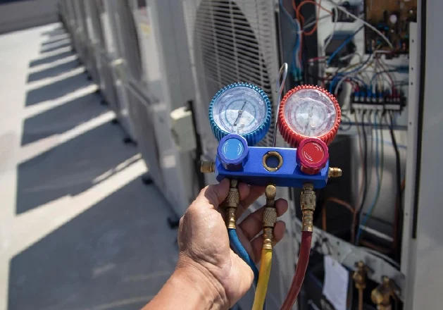Technician using refrigerant gauges to service rooftop commercial HVAC units in Columbus, Ohio